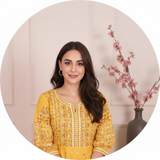 A circular portrait of influencer Sana Khan smiling, wearing the elegantly embroidered MALIKA dress against a soft cream back